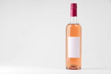 Bottle of tasty rose wine on white background, space for text