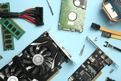 Photo of Graphics card and other computer hardware on light blue background, flat lay