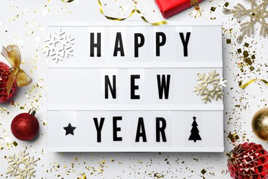 Photo of Lightbox with phrase Happy New Year and festive decor on white background, flat lay