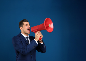 Handsome man with megaphone on blue background