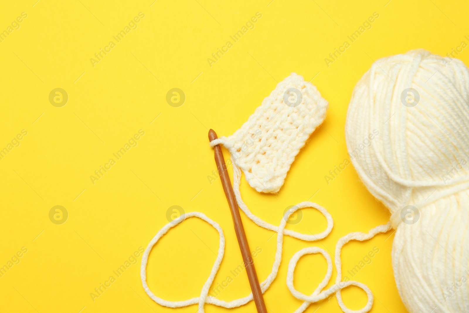 Photo of Knitting and crochet hook on yellow background, flat lay. Space for text