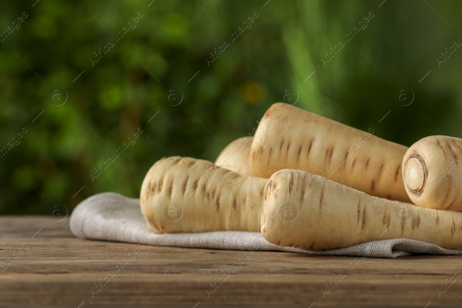 Photo of Delicious fresh ripe parsnips on wooden table outdoors, space for text