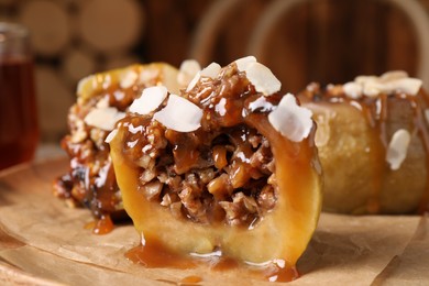 Photo of Half of delicious baked apple with nuts and caramel on parchment paper, closeup