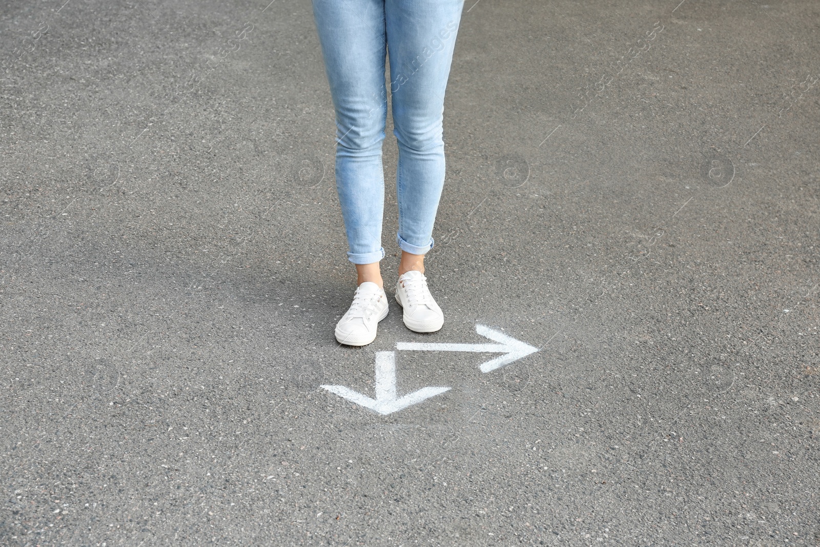 Photo of Woman standing near arrows on asphalt. Choice concept