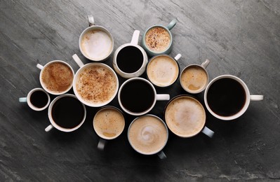 Photo of Many cups of different coffees on slate table, flat lay