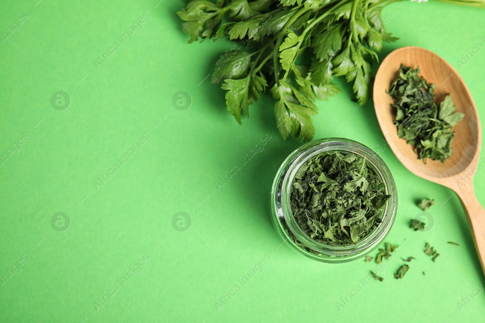 Photo of Flat lay composition with fresh and dried parsley on green background. Space for text