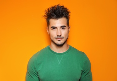 Young man with trendy hairstyle posing on color background