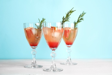 Glasses of grapefruit cocktails on table against color background