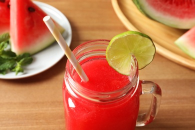 Photo of Summer watermelon drink with lime in mason jar on table, closeup