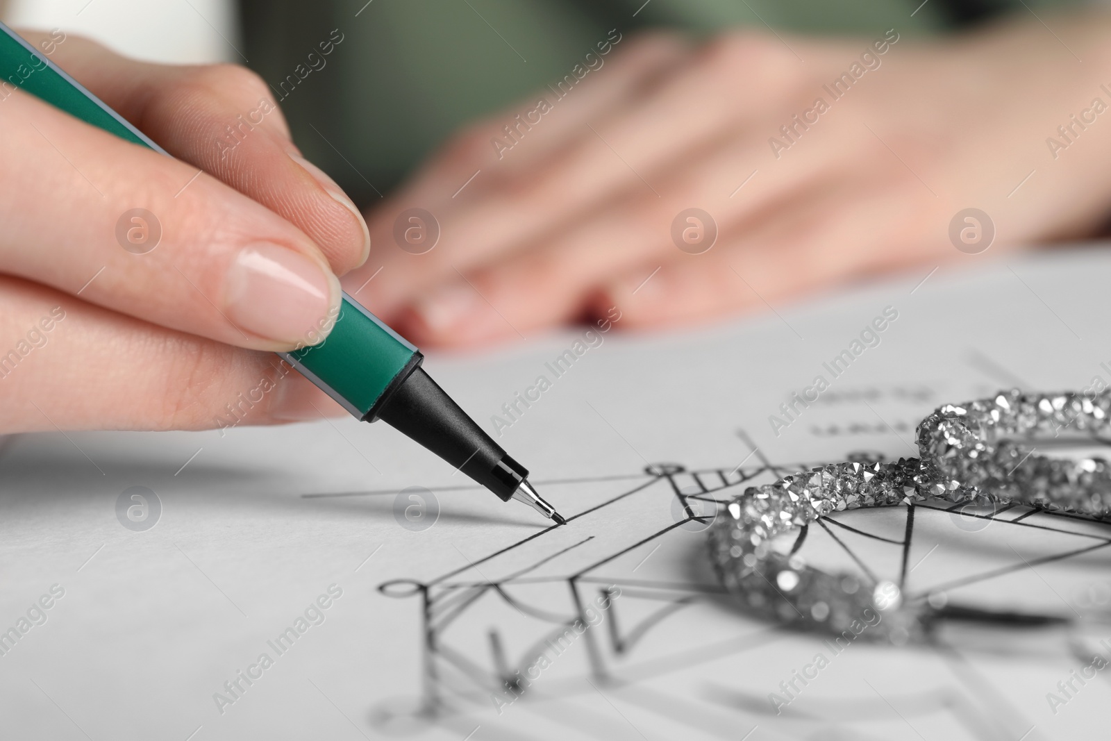 Photo of Jeweler drawing sketch of diamond on paper, closeup