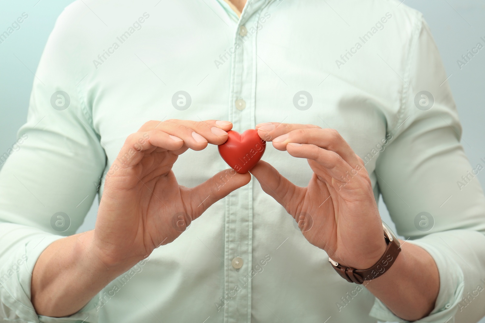 Photo of Man holding small red heart, closeup. Heart attack concept