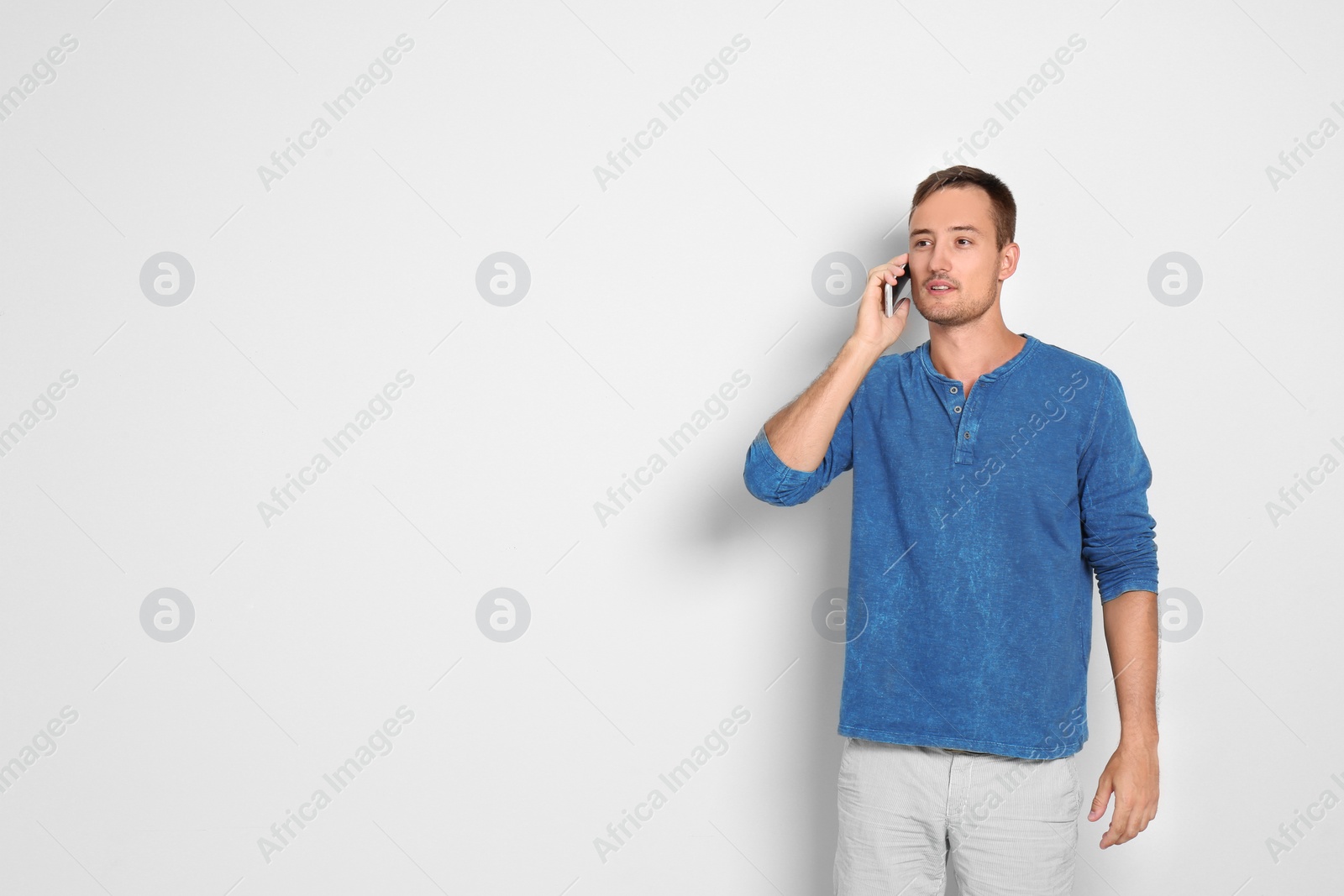 Photo of Young man talking on phone against white background. Space for text