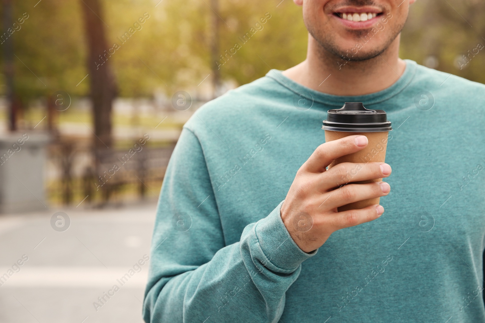 Photo of Man with takeaway coffee cup on city street, closeup. Space for text