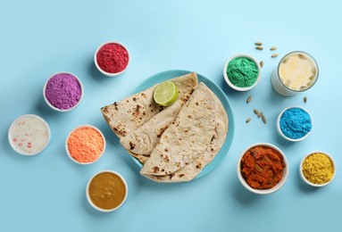 Traditional Indian food and color powder dyes on turquoise background, flat lay. Holi festival