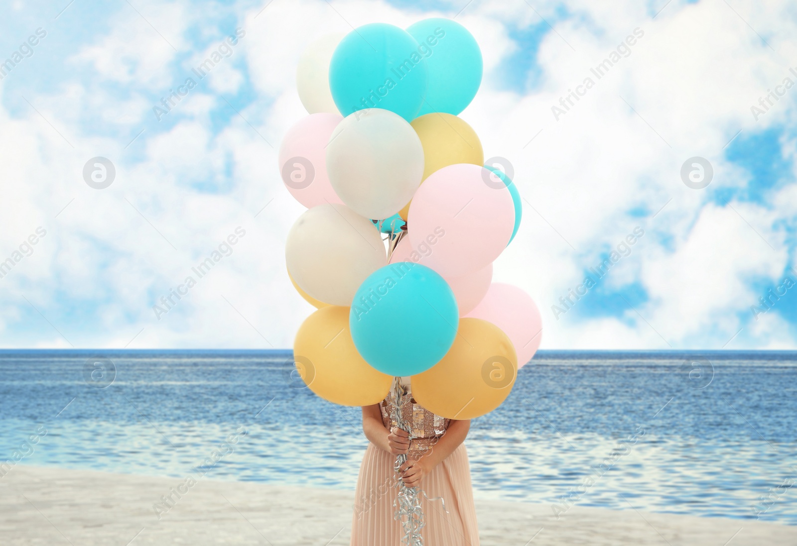 Photo of Young woman holding bunch of balloons outdoors