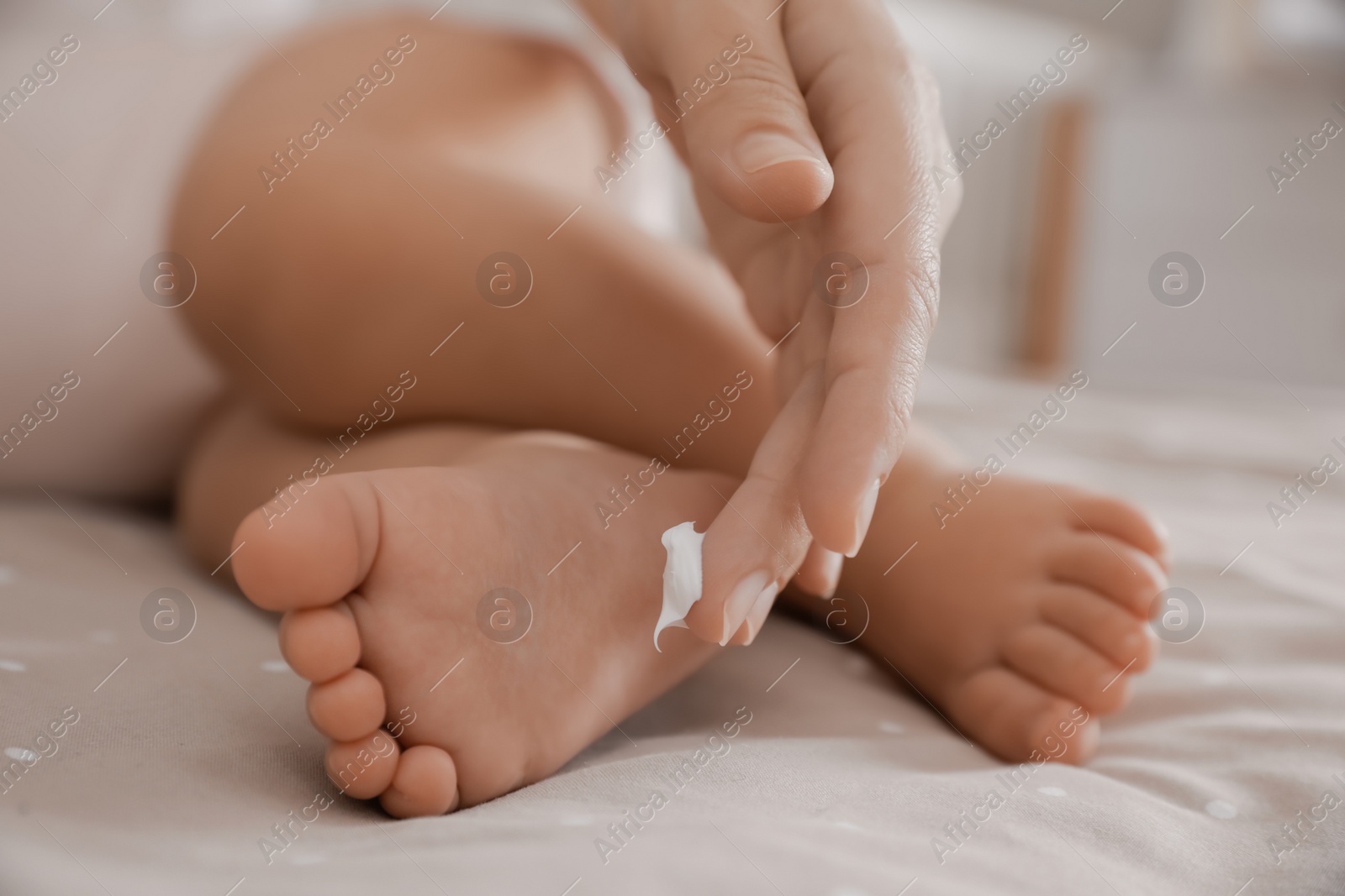 Photo of Mother applying moisturizing cream on her little baby at home, closeup