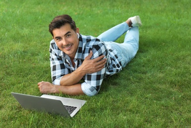 Portrait of young man with laptop outdoors