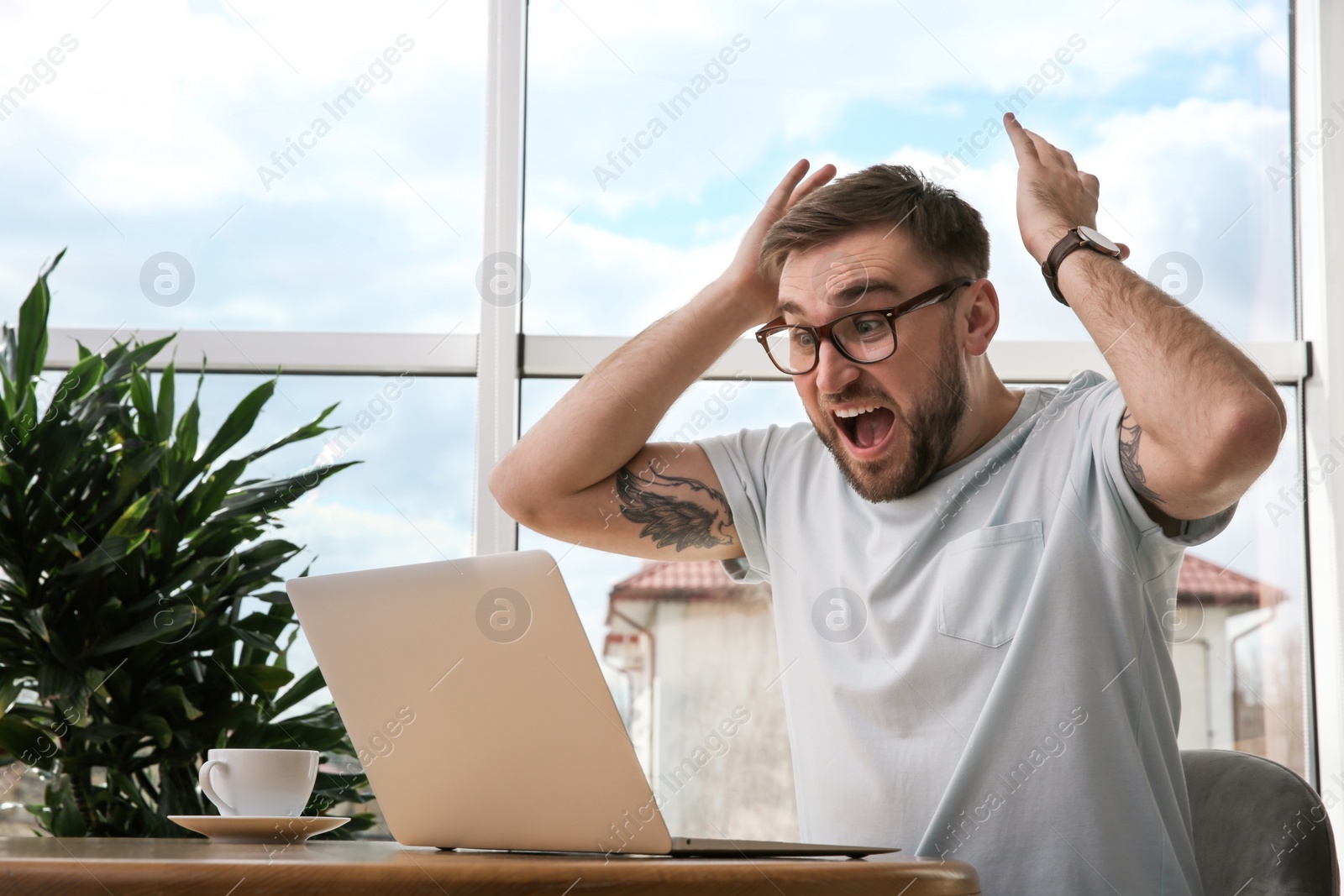 Photo of Emotional man participating in online auction using laptop at home