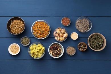 Many different dry herbs, flowers and seeds on blue wooden table, flat lay