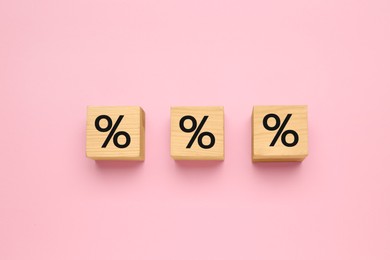 Photo of Wooden cubes with percent signs on pink background, flat lay