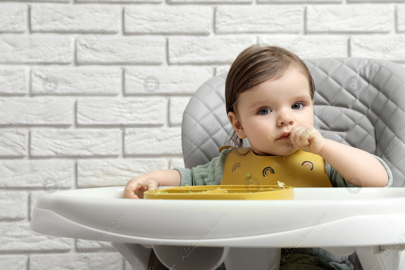 Photo of Cute little baby eating healthy food in high chair indoors. Space for text