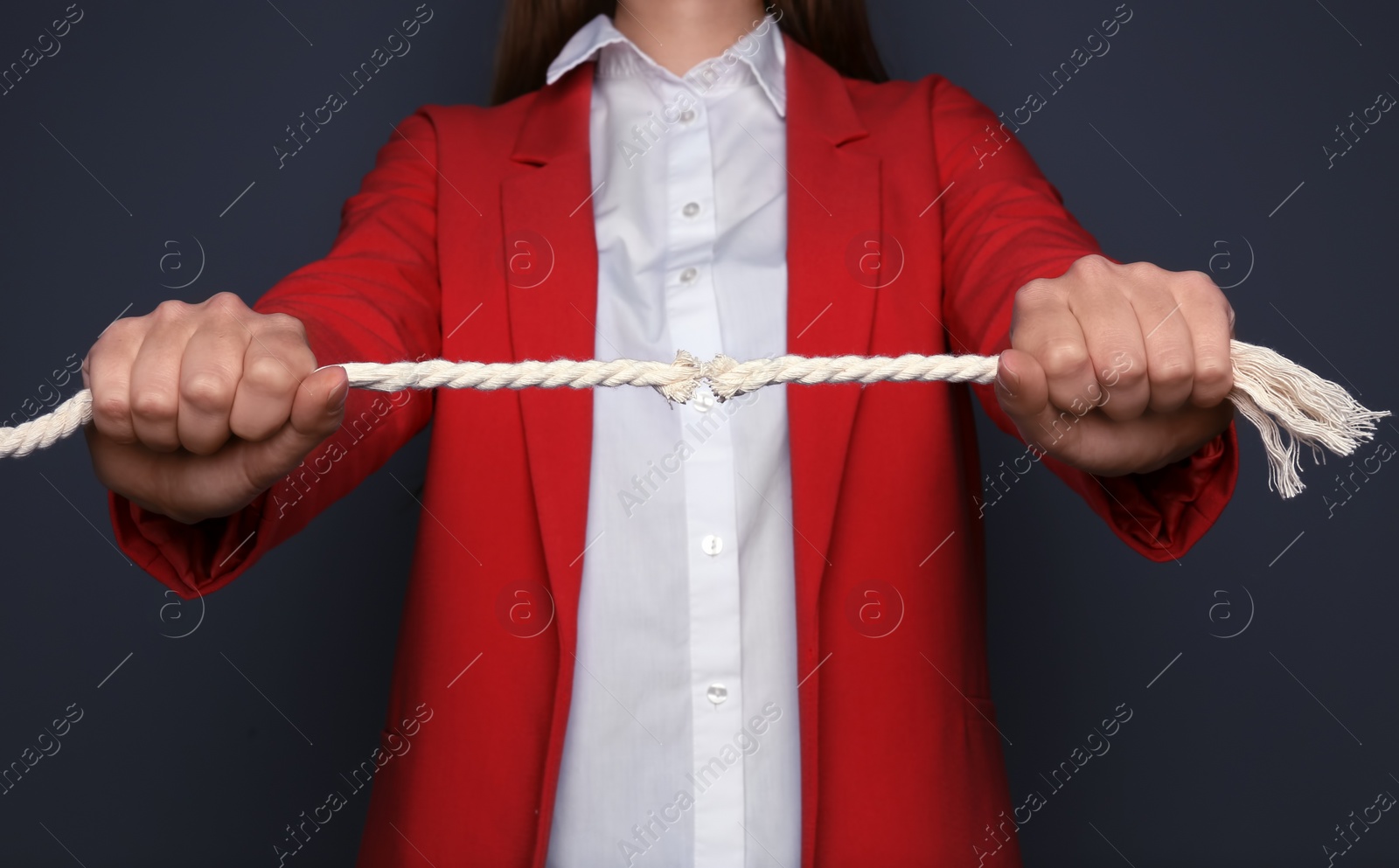 Photo of Woman pulling frayed rope with tension on dark background