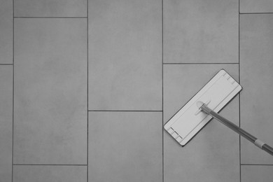 Cleaning grey tiled floor with mop, top view. Space for text