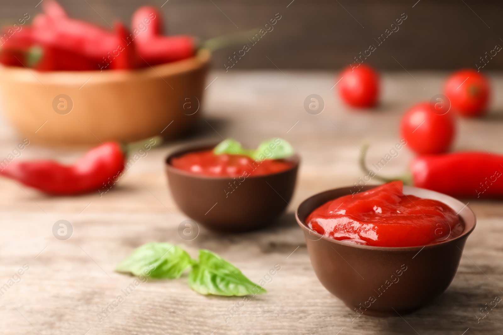 Photo of Bowls with spicy chili sauce on wooden table