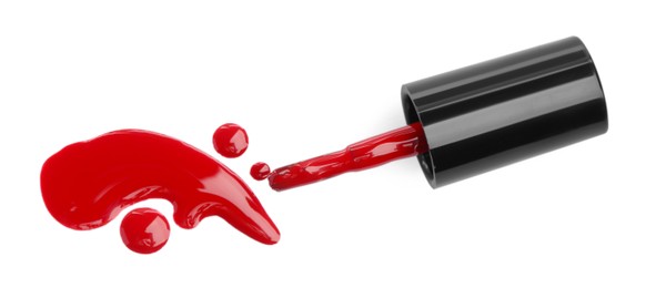 Photo of Brush and spilled red nail polish isolated on white, top view