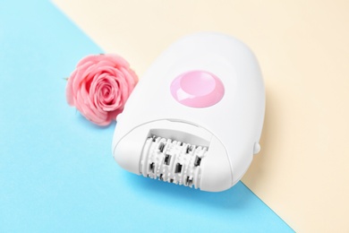 Photo of Modern epilator and flower on color background