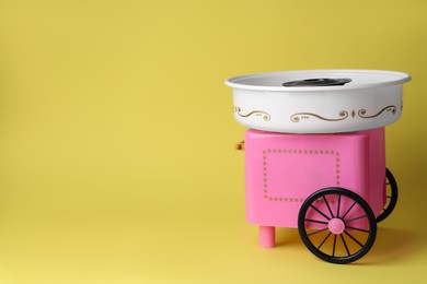 Portable candy cotton machine on yellow background, space for text