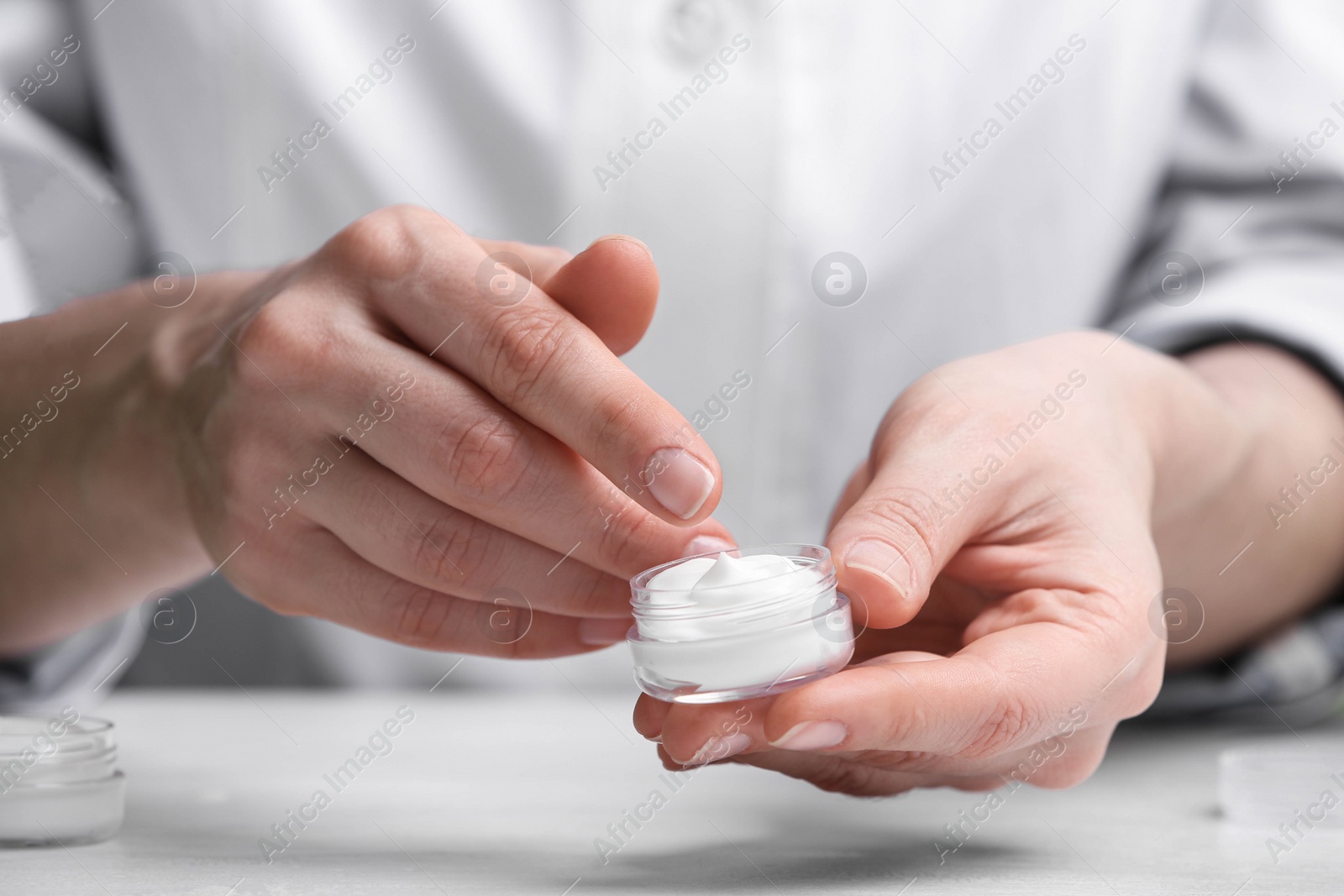 Photo of Woman with cream at table in cosmetic laboratory, closeup