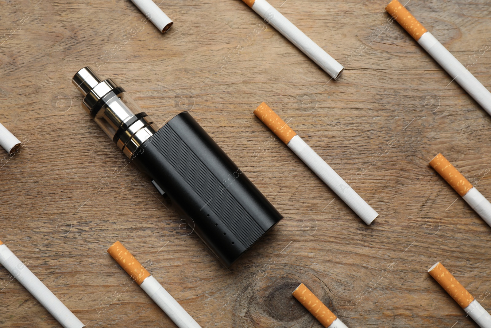 Photo of Cigarettes and vaping device on wooden background, flat lay. Smoking alternative