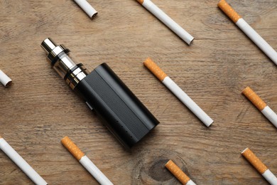 Photo of Cigarettes and vaping device on wooden background, flat lay. Smoking alternative