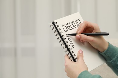 Photo of Woman filling Checklist with pen indoors, closeup. Space for text