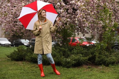 Young woman with umbrella in park on spring day