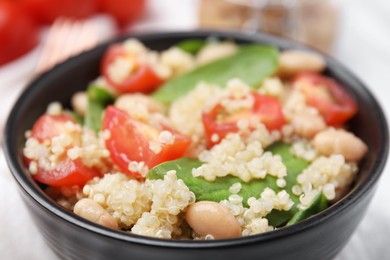 Delicious quinoa salad with tomatoes, beans and spinach leaves, closeup