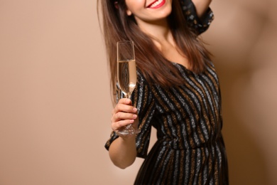 Happy woman with champagne in glass on color background, closeup