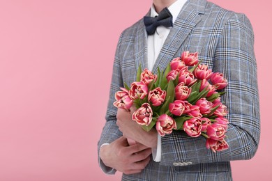 Man with beautiful bouquet on pink background, closeup. Space for text