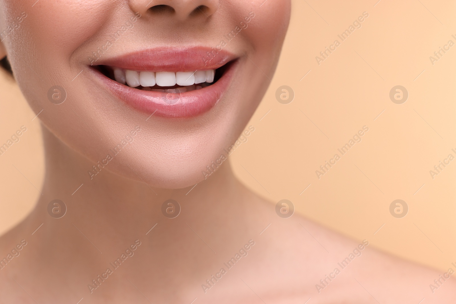 Photo of Woman with beautiful lips smiling on beige background, closeup