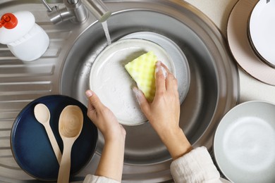 Photo of Woman washing plate in kitchen sink, above view