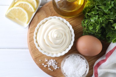 Photo of Fresh mayonnaise sauce in bowl and ingredients on white wooden table, flat lay