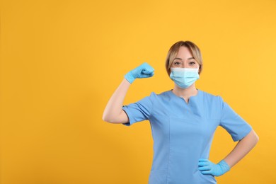 Photo of Doctor with protective mask showing muscles on yellow background, space for text. Strong immunity concept