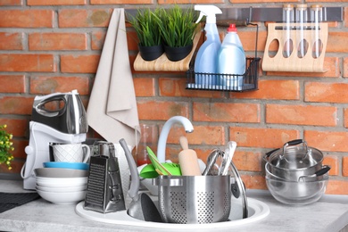 Kitchen sink with dirty dishes near brick wall