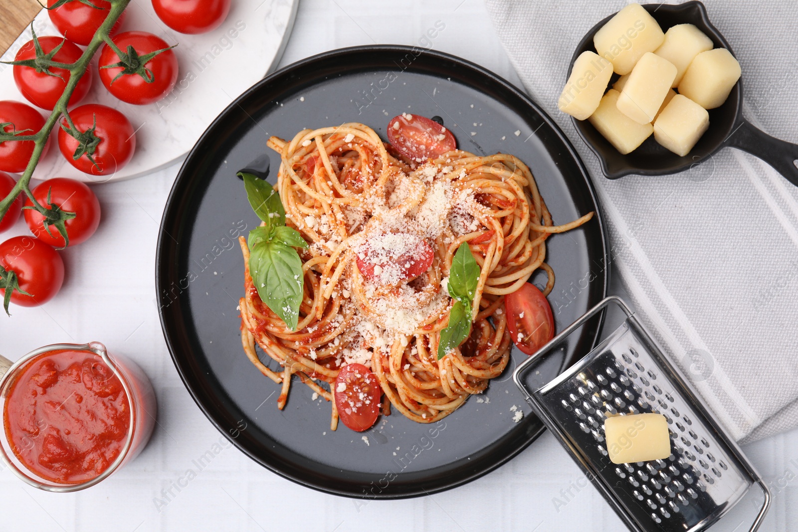 Photo of Tasty pasta with tomato sauce, cheese and basil served on white tiled table, flat lay