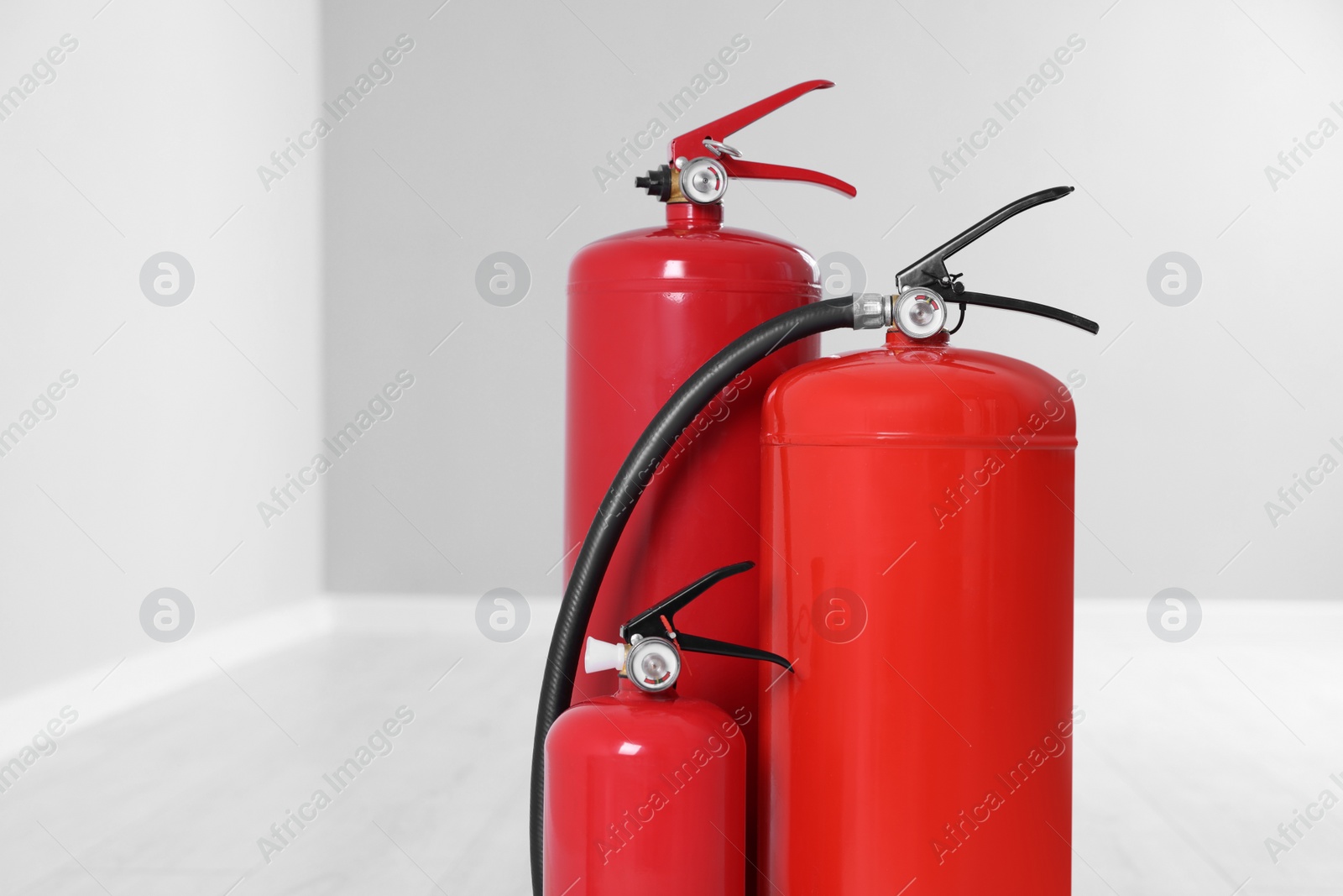 Photo of Fire extinguishers on floor indoors, space for text