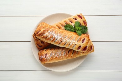 Photo of Fresh tasty puff pastry with sugar powder and mint on white wooden table, top view