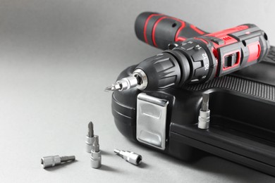 Electric screwdriver, drill bits and case on grey background. Space for text