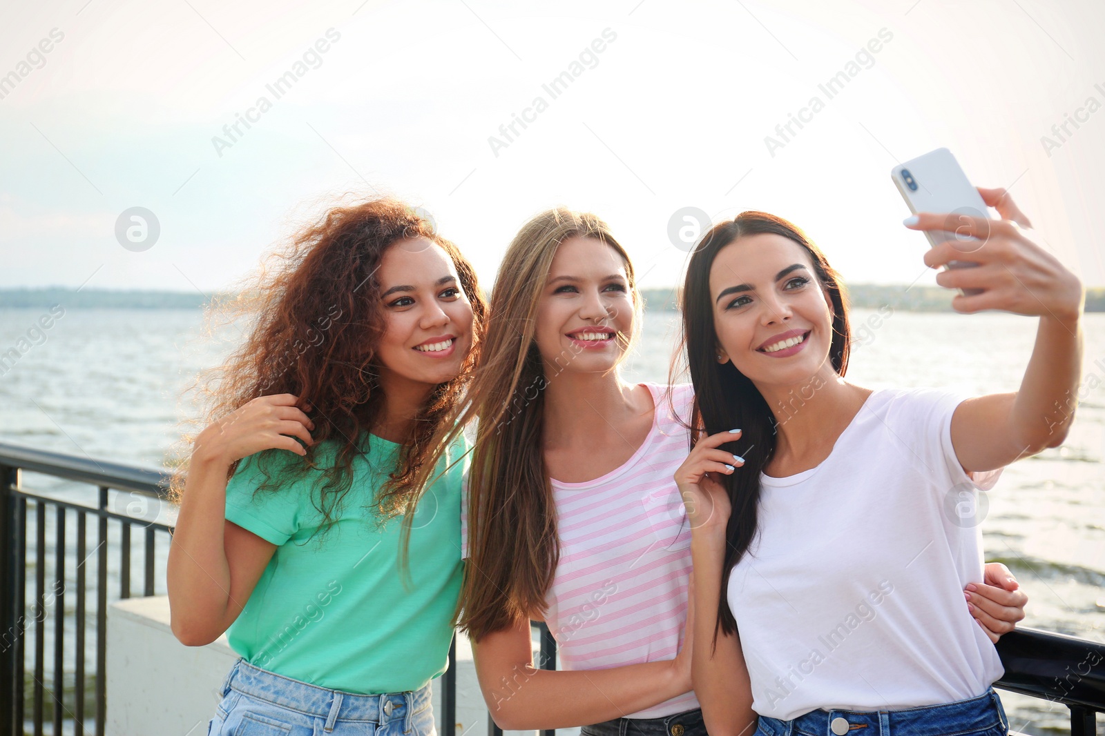 Photo of Happy young women taking selfie outdoors on sunny day