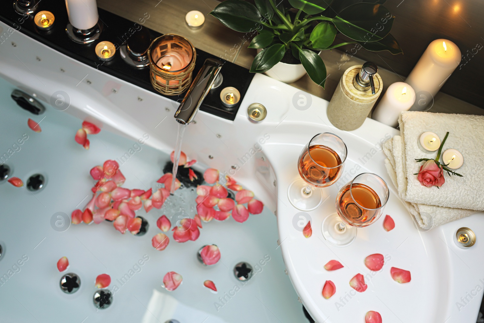 Photo of Bathtub with glasses of wine and candles indoors, above view. Romantic atmosphere